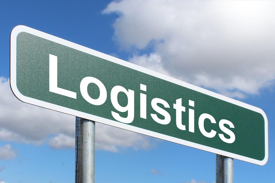 A green highway-style road sign with the word 'Logistics' prominently displayed against a blue sky background. This represents the logistics industry in a clear, symbolic way, though it doesn't specifically illustrate the scientific aspects of logistics. The simple, professional representation effectively communicates the logistics concept.